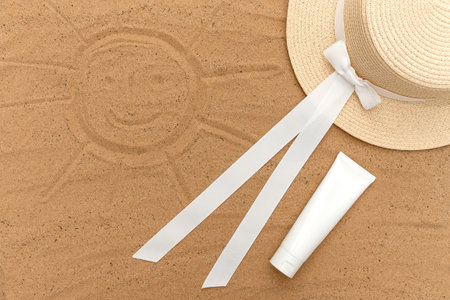 Sun hat on white sun cream sand. sun protection. The sun is painted on the sand.