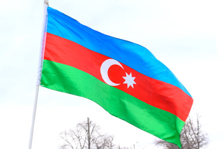 The wind flutters the flag of azerbaijan on the street against the blue sky. Symbol of patriotism.の写真素材