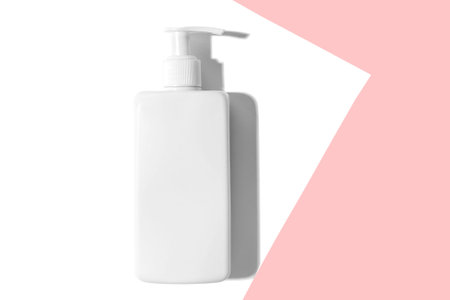 White dispenser on white-pink paper with cosmetic liquid. With hard shadow.の写真素材