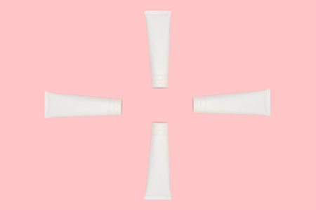 White cosmetic tube of skincare cream with hard shadow on pink background.の写真素材