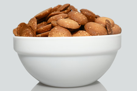 Small sesame biscuits in a white cup. On a gray background. close-up.の写真素材