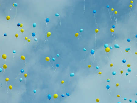 Balloons in yellow and blue shade on a cloudy sky background. High quality photo