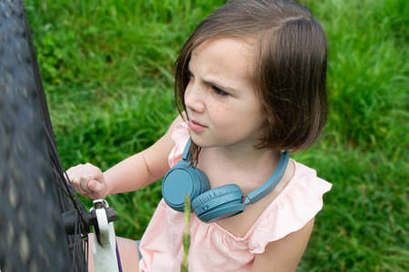 a child girl has damaged a bicycle wheel and is making repairs photo without processing. High...