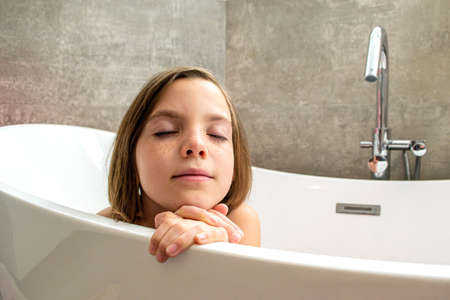 Relaxed young girl model wears towel wrapped on head, feels refreshed after taking shower, has...
