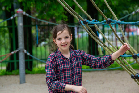 Close up happy little child girl play and sitting on the swing in the nature park. Teen girl on a...