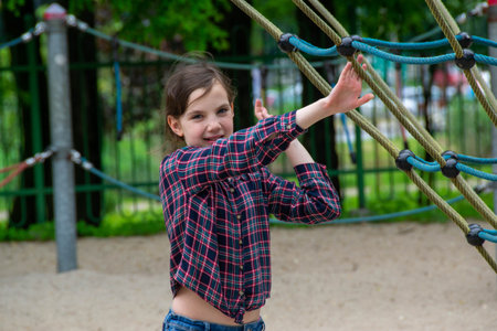 Close up happy little child girl play and sitting on the swing in the nature park. Teen girl on a swing in the summer park. High quality photoの写真素材