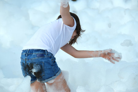 happy girl with foam on her head, in wet clothes at a foam party, in wet clothes at a foam party or holiday on a sunny hot summer day. High quality photoの写真素材