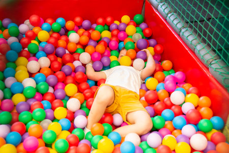 Boy playing on the playground, in the children's maze with balls. Multi-colored balls, soft walls...
