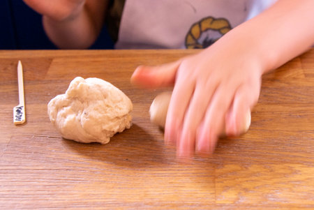 happy boy in the kitchen. Child roll out the dough with a rolling pin. Holiday and family leisure concept. Mother with child making biscuits on table. High quality photoの写真素材