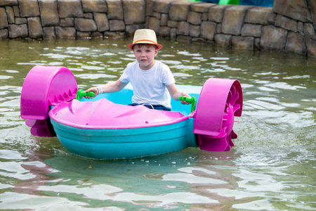 Kid playing rowing water paddle boat. Soft focus. A little girl rides a colorful boat on a pool in a resort. High quality photoの写真素材