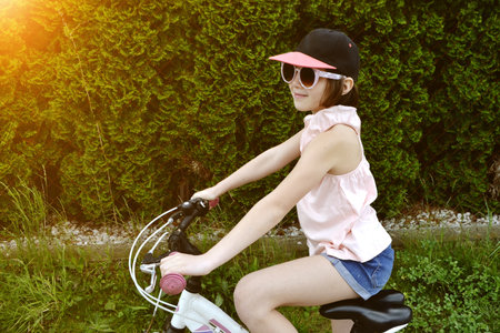 Young girl cyclist enjoy the beautiful sunrise on summer forest trail. Close-up portrait of a happy...