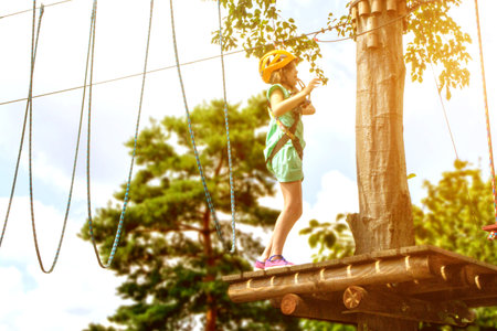 Adventure climbing high wire park - child on course in mountain helmet and safety equipment. High quality photoの写真素材