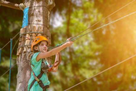 Adventure climbing high wire park - child on course in mountain helmet and safety equipment. High quality photoの写真素材
