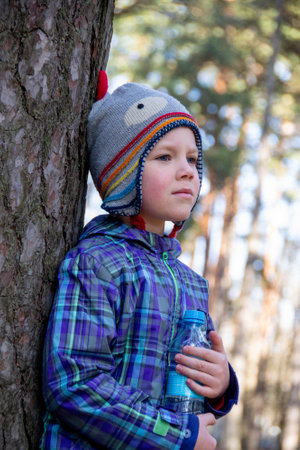 Boy spends happy time outdoors in forest enjoying autumn nature. A handsome little blond boy in a...