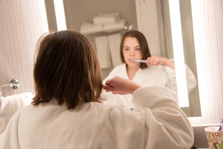 Beautiful girl in a Bathrobe posing in the interior of the room. Portrait of a cute beautiful girl in a white towel and Bathrobe. The morning of the procedure. High quality photoの写真素材