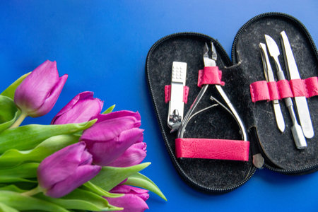 Tools and cosmetics needed for nail styling on a blue background. Pedicure set isolated on white. pink cosmetic bag and a set of women's accessories. High quality photoの写真素材