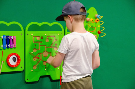 Child plays Montessori game. Kid collects wooden toy sorter. Multicolored geometric shapes, circle, square, triangle, rectangle. Early childhood development. High quality photoの写真素材