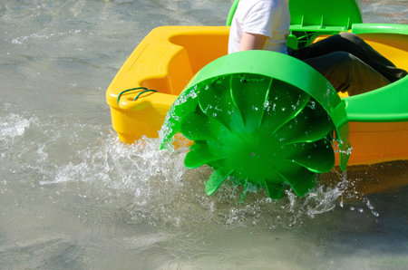 Kid playing rowing water paddle boat. Soft focus. A little girl rides a colorful boat on a pool in a resort. High quality photo.の写真素材