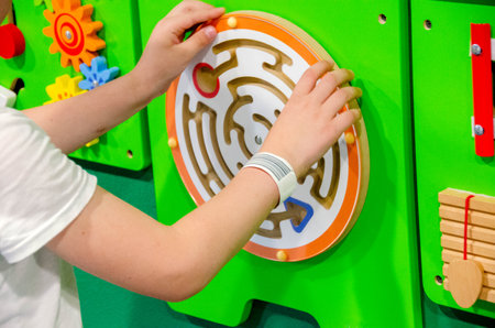 Child plays Montessori game. Kid collects wooden toy sorter. Multicolored geometric shapes, circle, square, triangle, rectangle. Early childhood development. High quality photoの写真素材