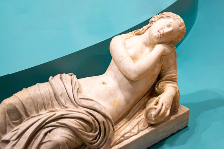 Cartoonishly large bosom on marble goddess sculpture. Museum photography. Ancient Roman marble statue. Young person figure statue isolated on colored background. Antique sculpture. High quality photoの写真素材