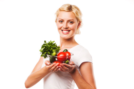 Young girl eating fresh vegetable salad on white backgroundの写真素材