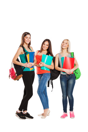 Three happy students girl standing together with fun, while smiling and looking at camera isolated on white background.の写真素材