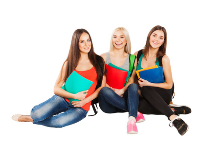 Three happy students sitting together with fun, while smiling and looking at camera isolated on white background.の写真素材
