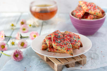 Homemade cookies with colored sugar with tea on a light wooden background. The concept of breakfast.