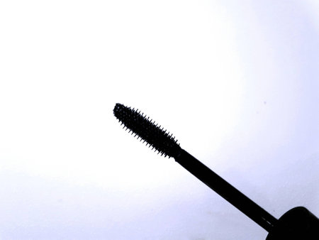 Black mascara applicator on a white background representing beauty and femininityの素材