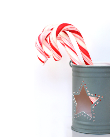 Sweet Christmas candy canes in a light gray cup with a star holeの写真素材