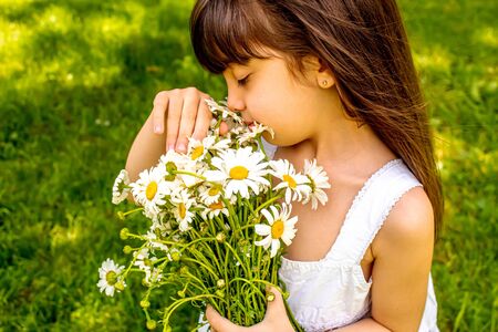 Girl with daisies in hands on the field. Selective focus.の写真素材