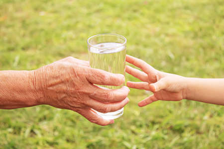 Grandmother giving a glass of clean water to a child. Selective focus.の写真素材