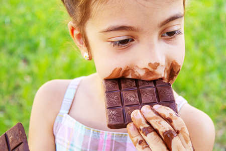 A sweet-toothed child eats chocolate. Selective focus. nature.