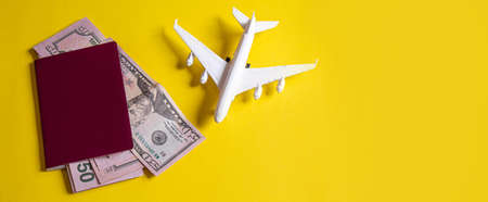 Travel preparation concept of airplane, money, passport, on yellow background. Selective focus.holidaysの写真素材