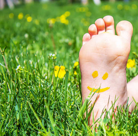 Children's feet with a pattern of paints smile on the green grass. Selective focus. nature.の写真素材