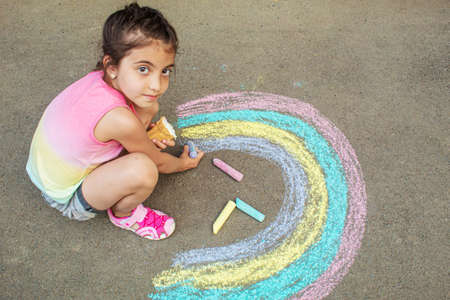 A child draws a rainbow on the asphalt. Selective focus. kid.の写真素材