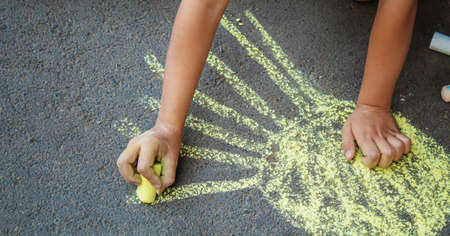 child draws with chalk on the pavement. Selective focus.の写真素材