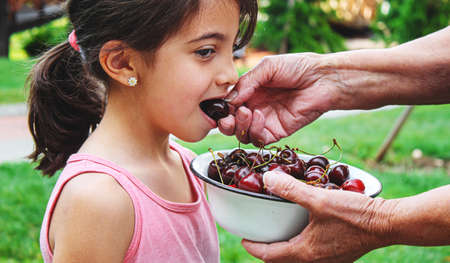 grandparents feed the child with cherries.selective focus.natureの写真素材