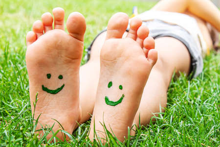Childrens feet with a pattern of paints smile on the green grass. Selective focus.