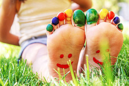 Children's feet with a pattern of paints smile on the green grass. Selective focus. nature.の写真素材