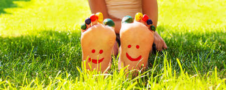 Children's feet with a pattern of paints smile on the green grass. Selective focus. nature.の写真素材