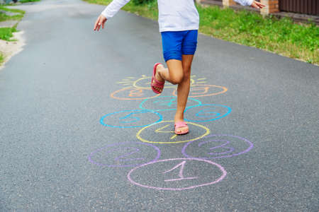 Child jumping classics on the pavement. Selective focus.natureの写真素材