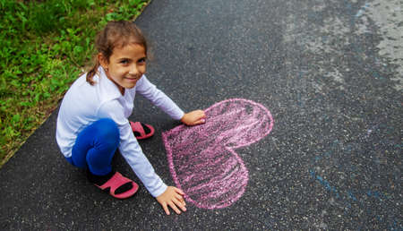 The child draws with chalk on the asphalt. Selective focus.natureの写真素材