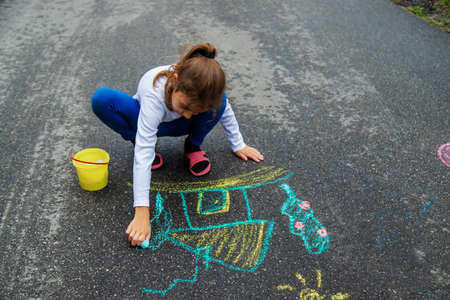 The child draws with chalk on the asphalt. Selective focus.natureの写真素材
