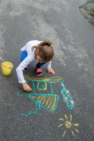 The child draws with chalk on the asphalt. Selective focus.natureの写真素材