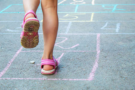 Child jumping classics on the pavement. Selective focus.childの写真素材