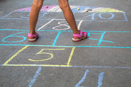 Child jumping classics on the pavement. Selective focus.childの写真素材