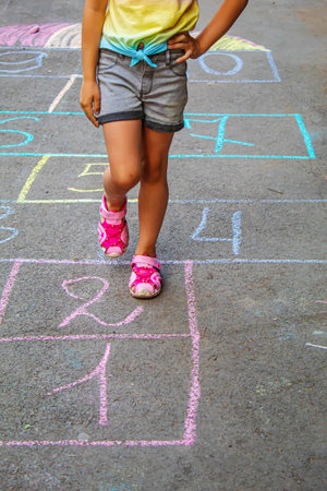 Child jumping classics on the pavement. Selective focus.childの写真素材