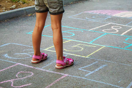 Child jumping classics on the pavement. Selective focus.childの写真素材