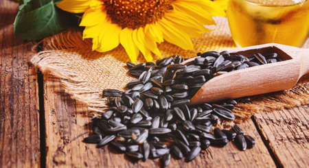 Sunflower seeds and oil bottle on old wooden background. Selective focus.natureの写真素材